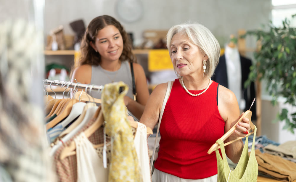 Two positive women choosing something for summer in clothing store