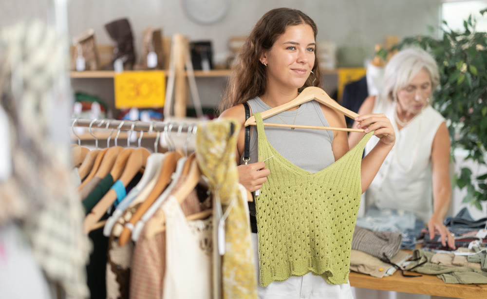 Young woman choosing top in clothing store