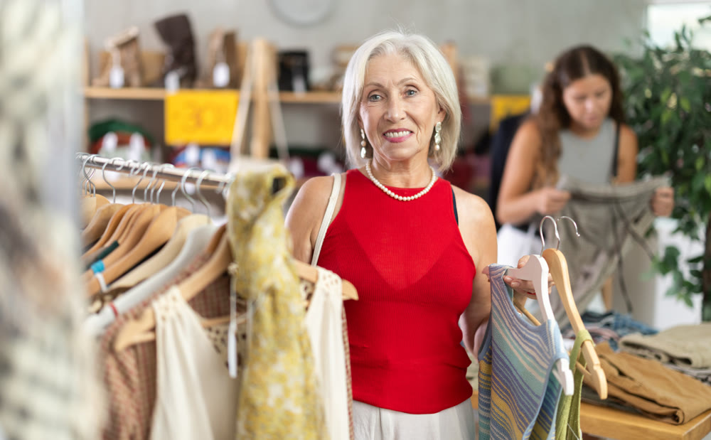 Positive mature woman choosing something for summer in clothing store