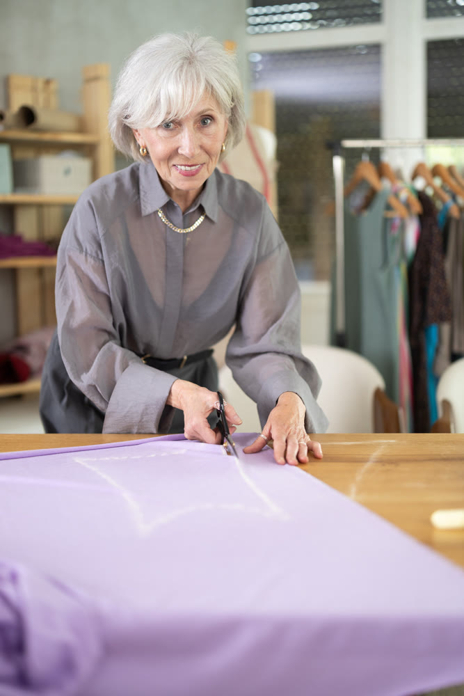 Mature dressmaker cutting fabric