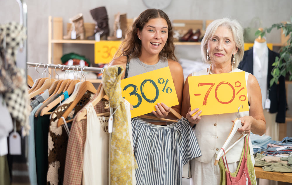 Two happy women of different ages holding sign saying discount