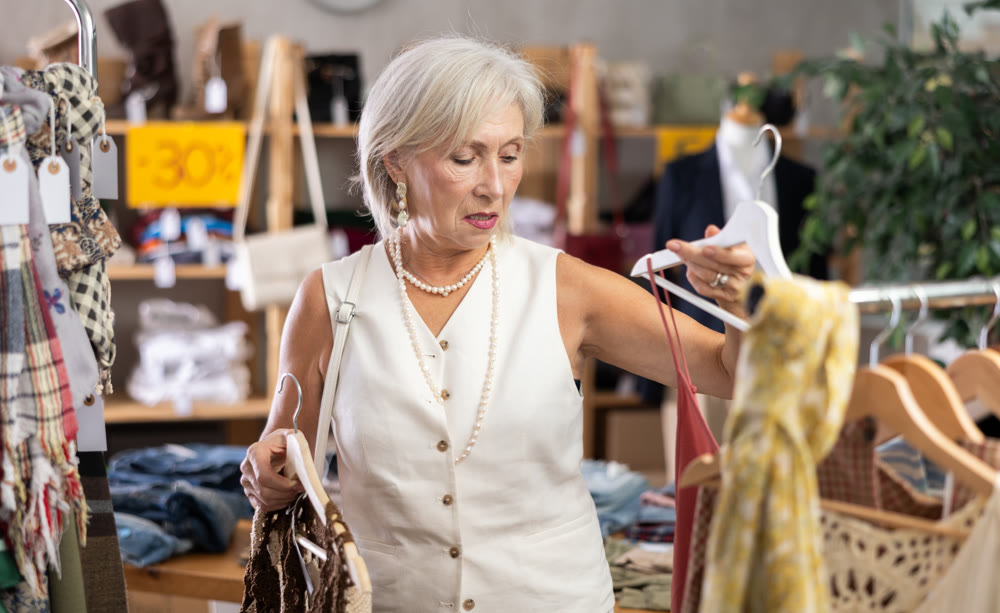 Attentive mature woman choosing something for summer in clothing store