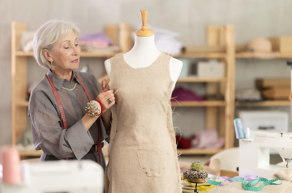 Mature female dressmaker working with mannequin in sewing workshop