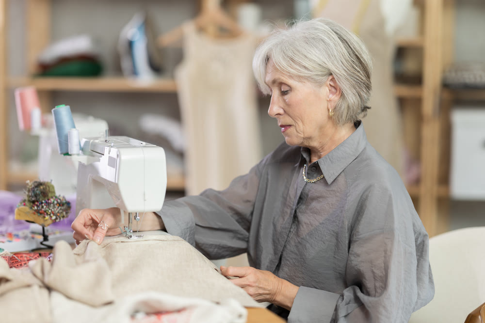 Woman seamstress sews on sewing machine in workshop