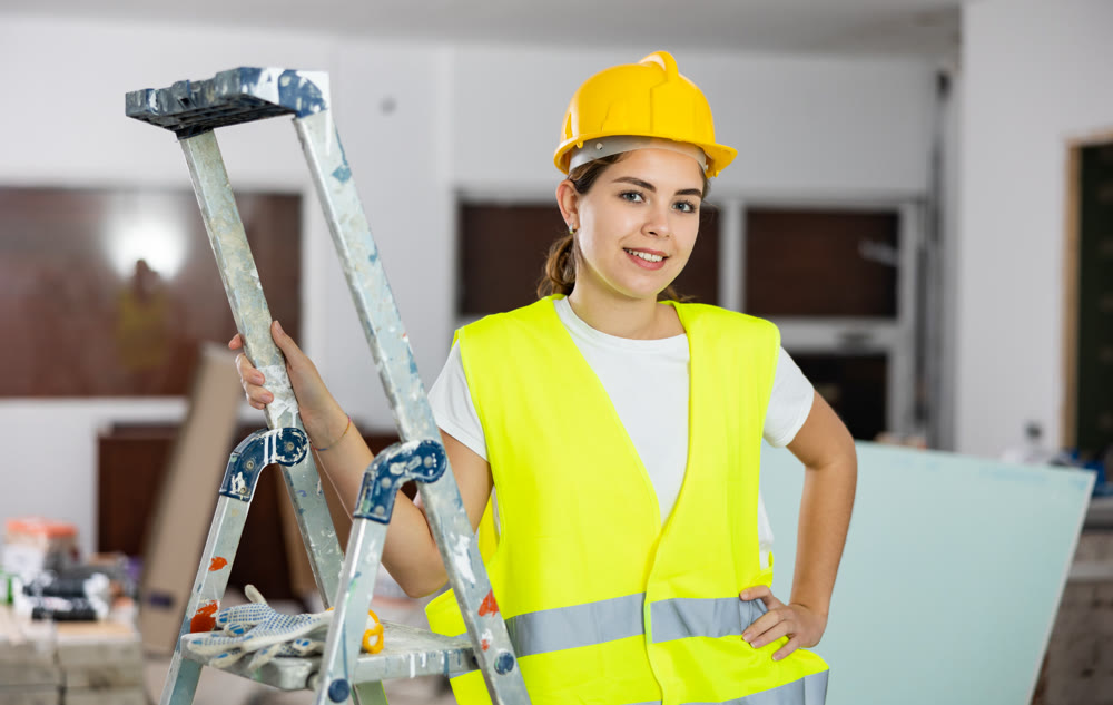 Portrait of female foreman in protective yellow vest and hard hat in room being renovated