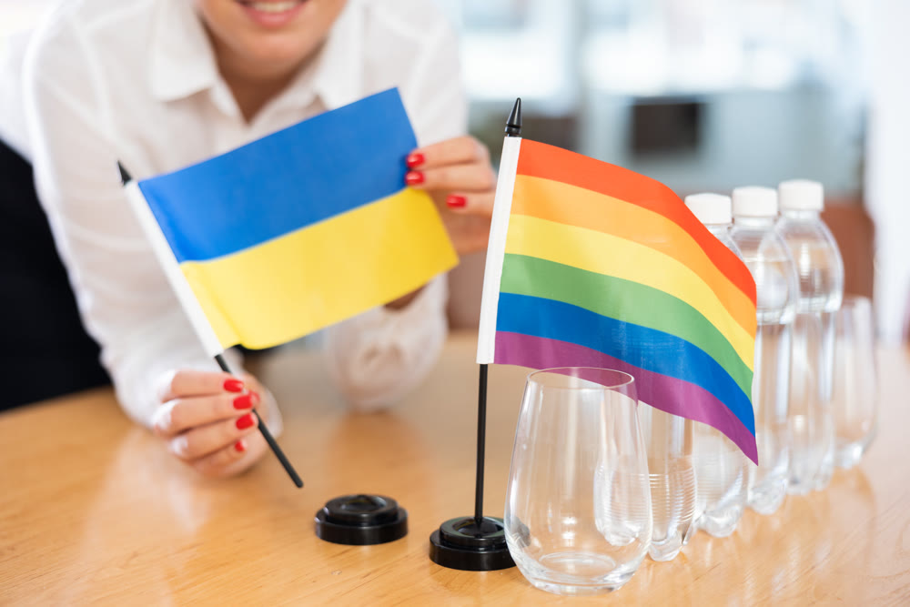 Young woman puts flags of Ukraine and LGBT on table in office