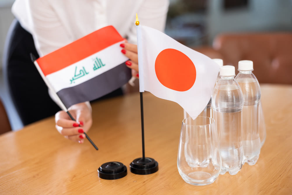 Flags of Iraq and Japan as symbol of diplomatic relations on negotiating table