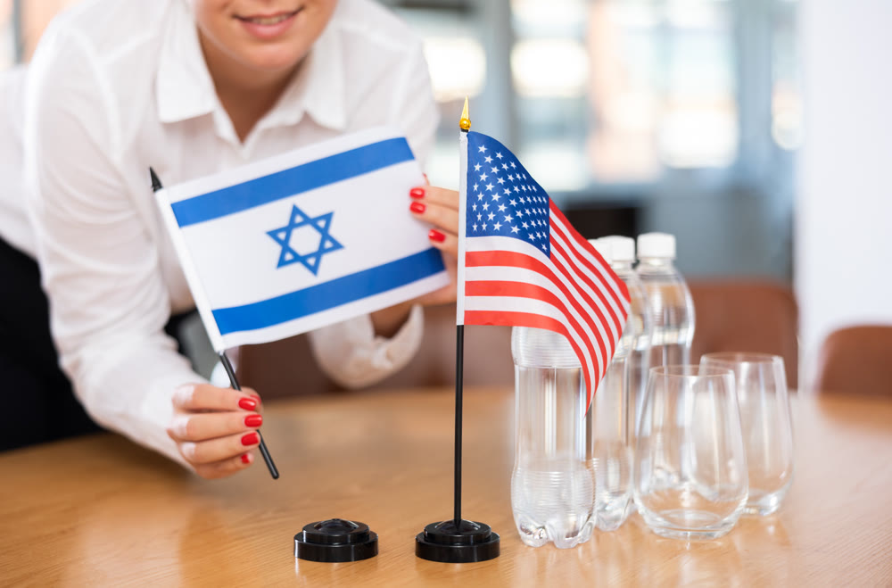 Flags of Israel and USA stand on negotiating table in office