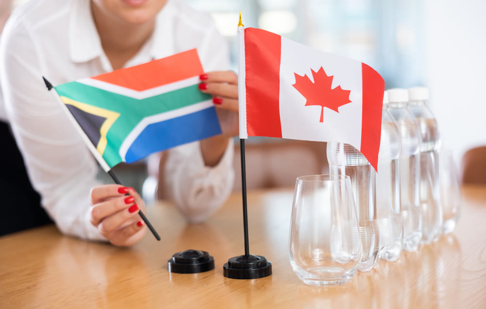 Unrecognizable girl sets midget flags of Canada and South Africa before international negotiations