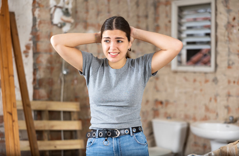 Puzzled young woman examining her house during renovation