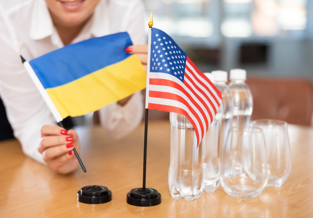 Office coordinator setting flags of Ukraine and United States on table