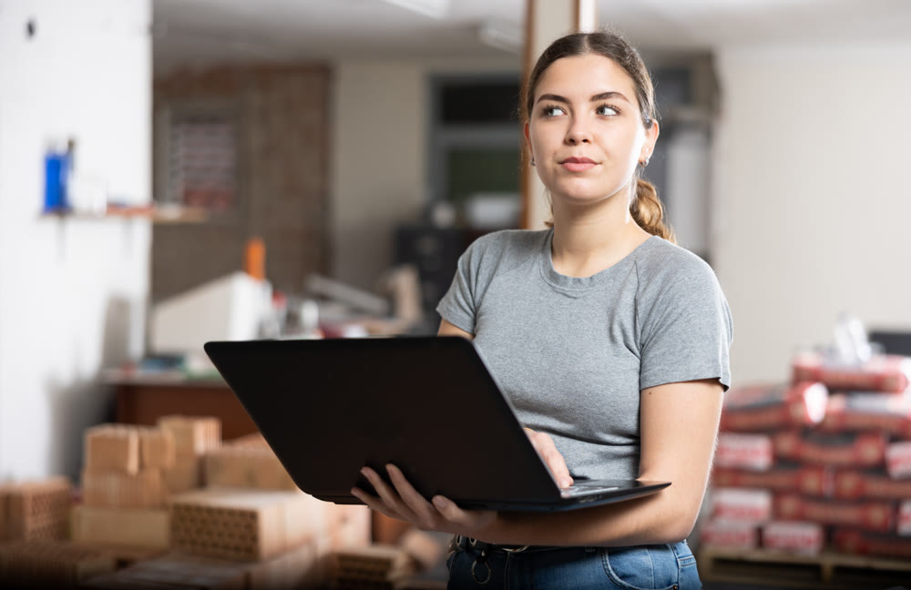 Young woman using laptop in house during renovating