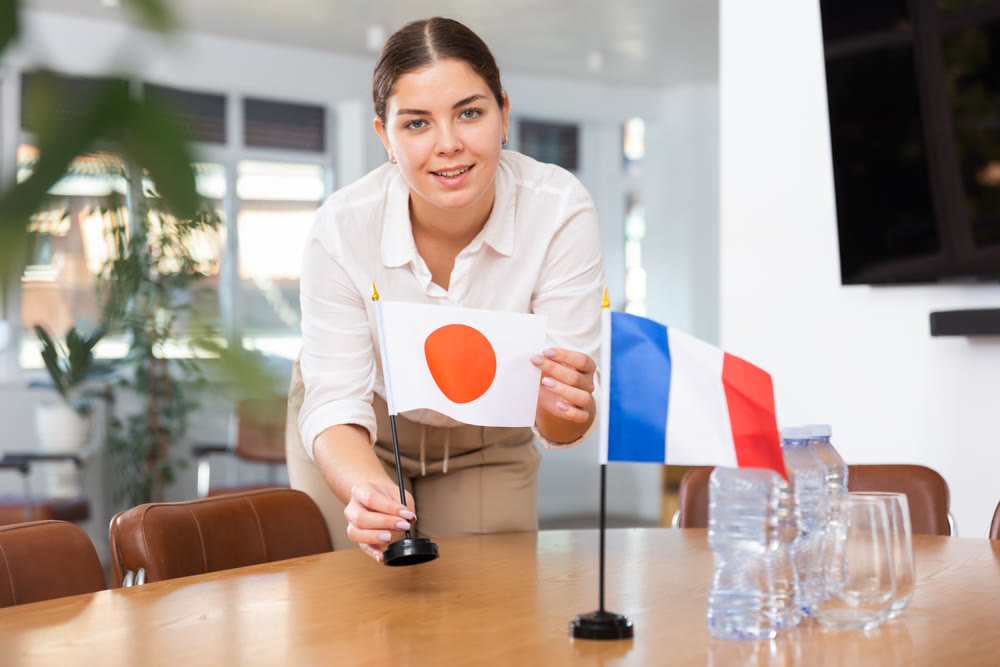 Employee of delegation prepares negotiating table - sets up flag of Japan and France