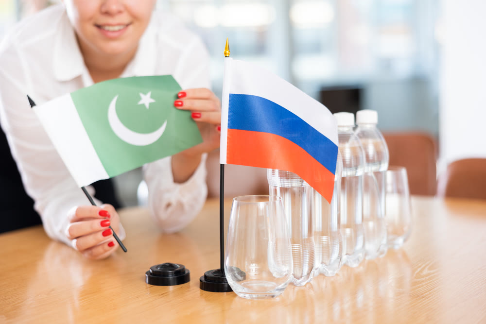 Unrecognizable girl sets midget flags of Russia and Pakistan before international negotiations