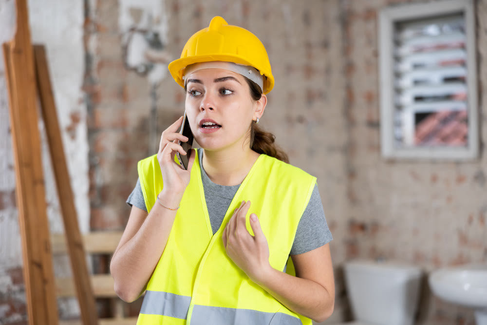 Smiling female foreman talking on phone during break at construction site