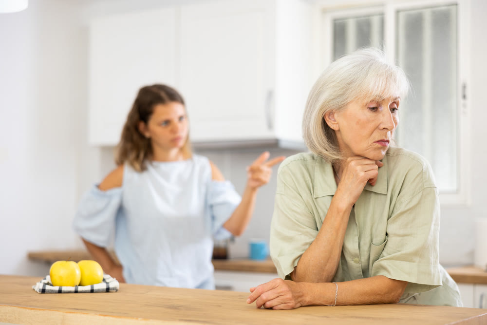 Quarrel of an elderly mother and adult daughter in the kitchen. Adult daughter is unhappy with elderly mother