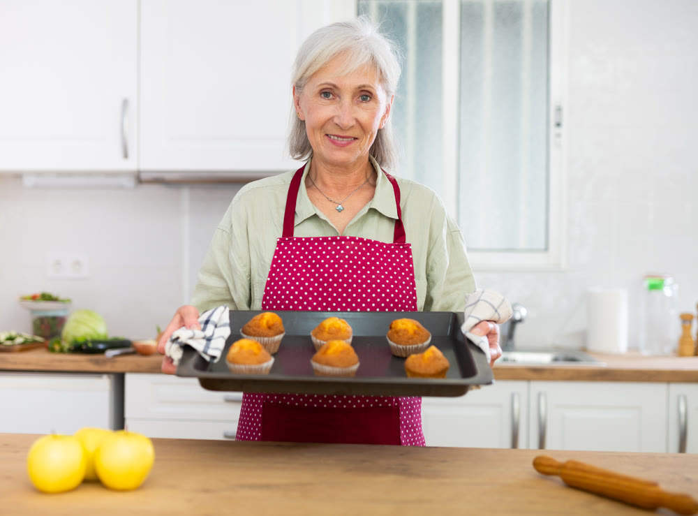 Mature woman baking vanilla muffins at home