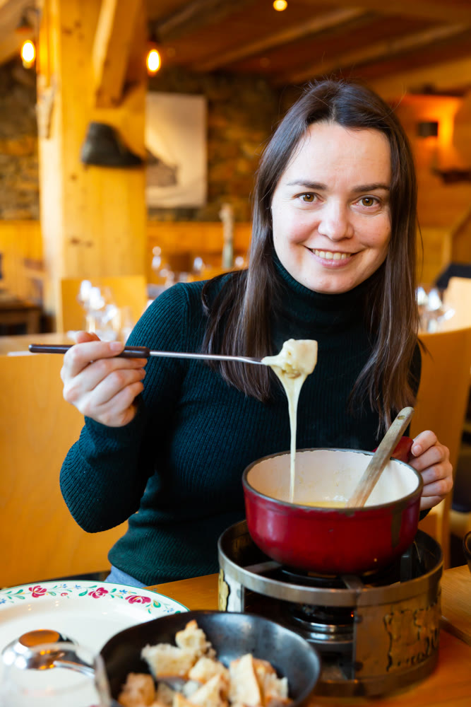 Woman having meal in Swiss restaurant, eating fondue