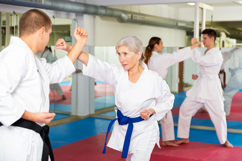 Portrait of woman wearing white kimono sparring with male opponent during martial arts training