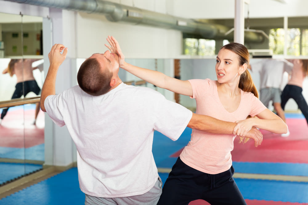 Girl practicing palm blow in chin in self defence training with coach