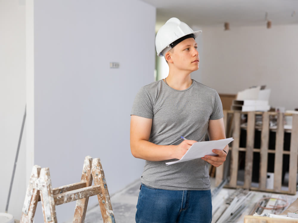 Young man checking project documentation in apartment during repair works