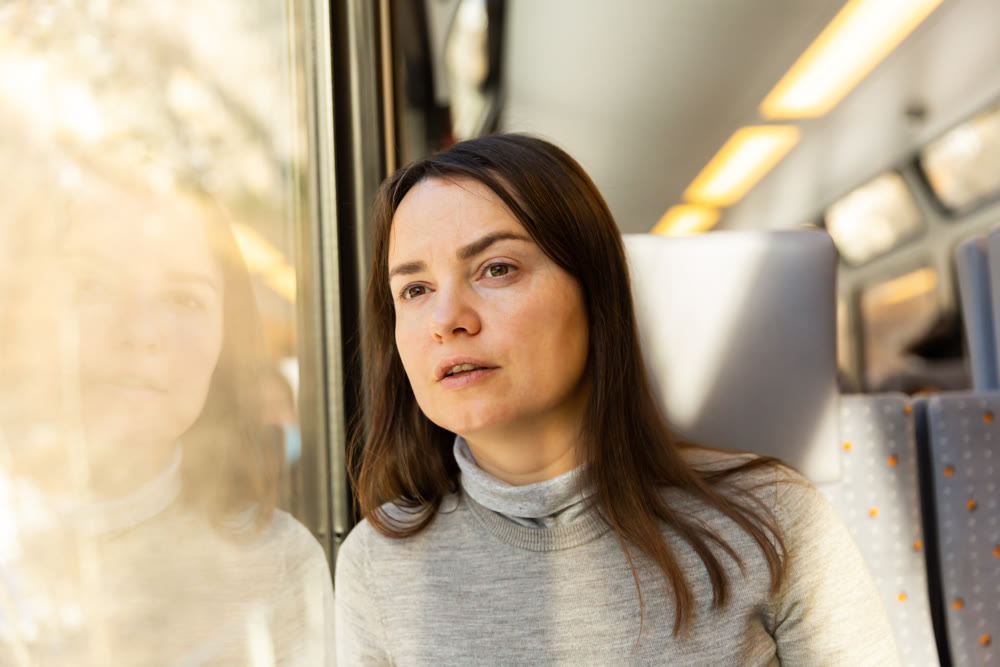 Female traveler looking at landscapes outside window in train