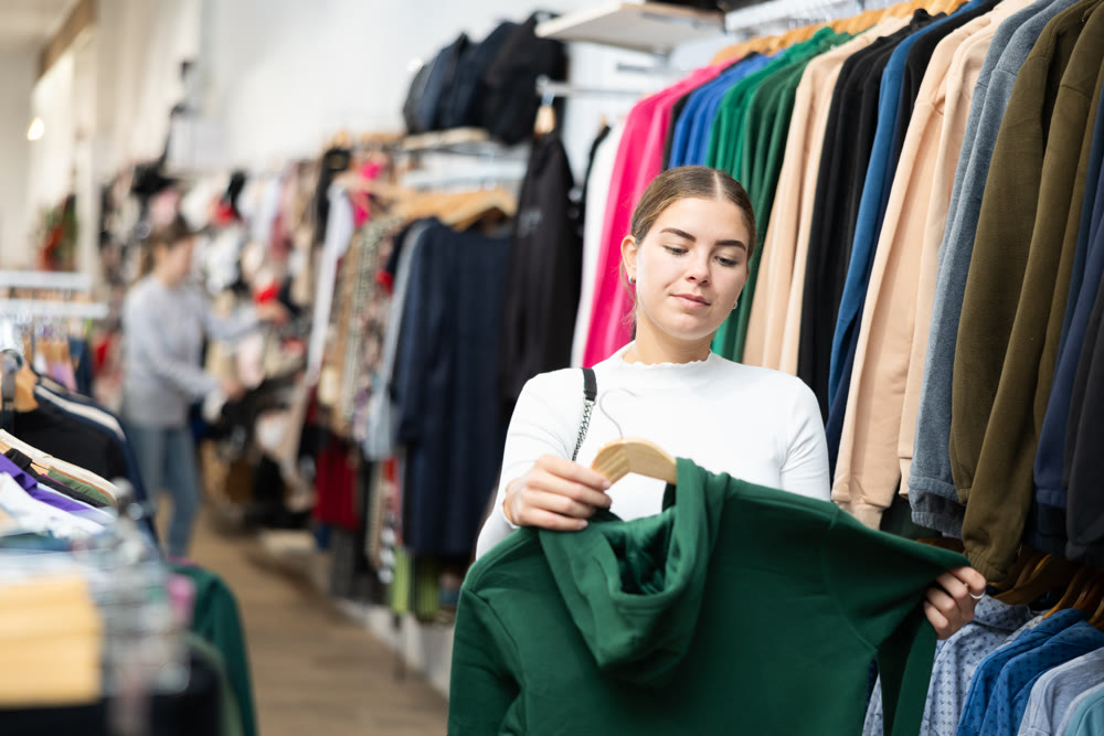 Young woman shopping for warm casual clothing in retail shopping store