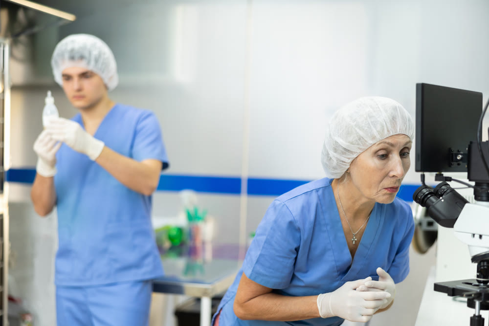 Senior female doctor looks through microscope in laboratory department of veterinary clinic