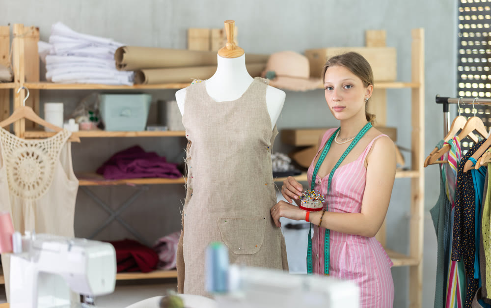 Woman seamstress adjusts clothes on mannequin