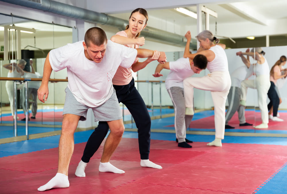 Girl performing elbow strike and wristlock to man in self defence training