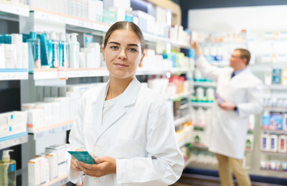 Young female pharmacist demonstrating lubricant in chemist's shop
