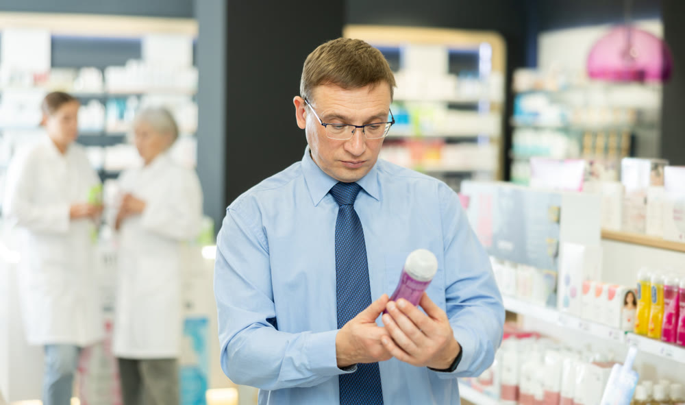 Man carefully selects intimate hygiene items or lubricant in pharmacy