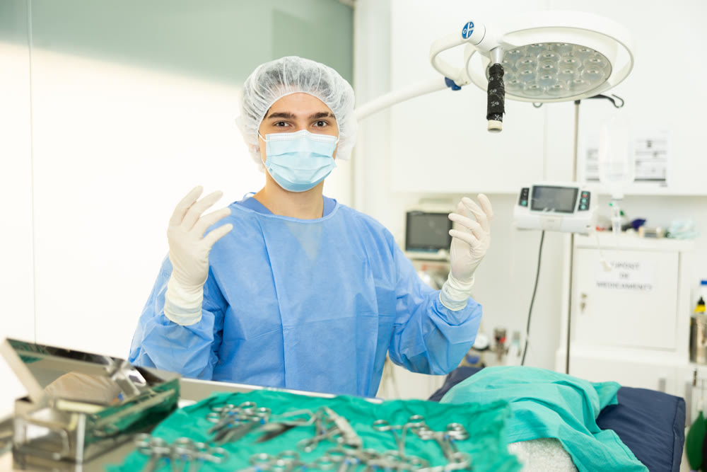Young veterinarian in surgical outfit standing in veterinary operating room