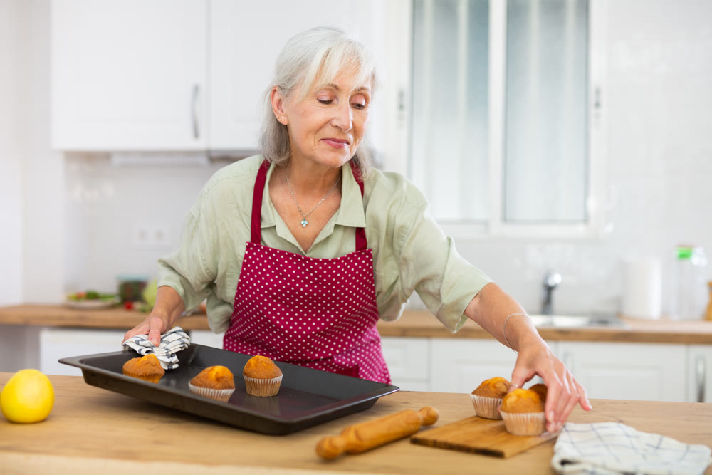 Mature woman baking vanilla muffins at home