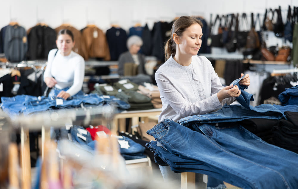 Satisfied woman chooses jeans in clothing store