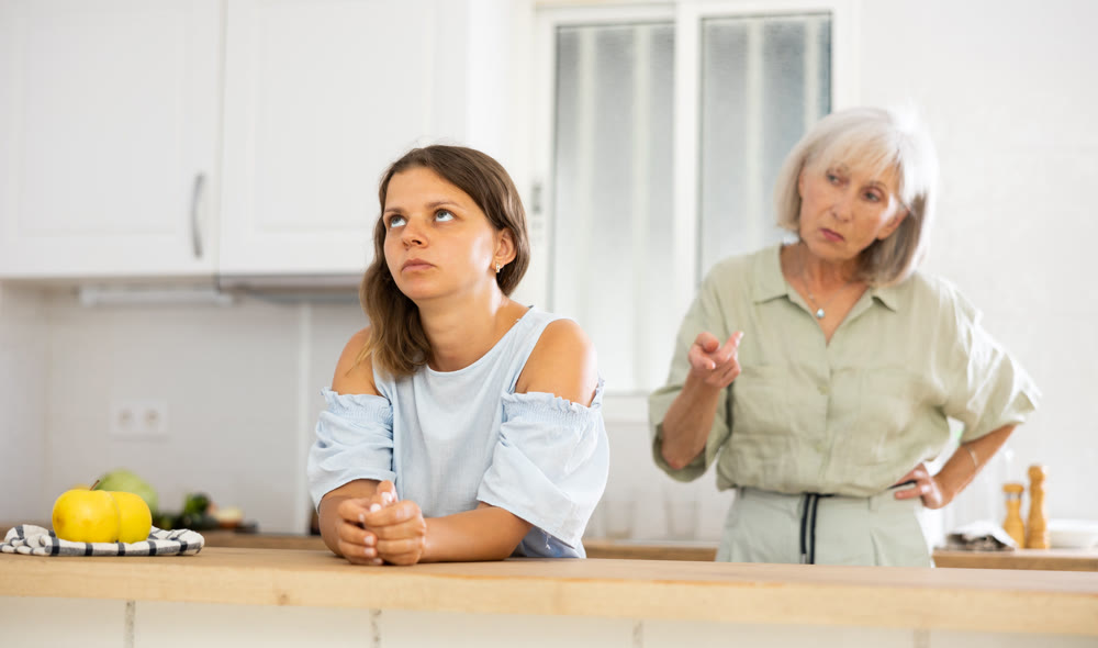 Upset girl at home kitchen while worried elderly mother reprimanding her. Family conflicts concept