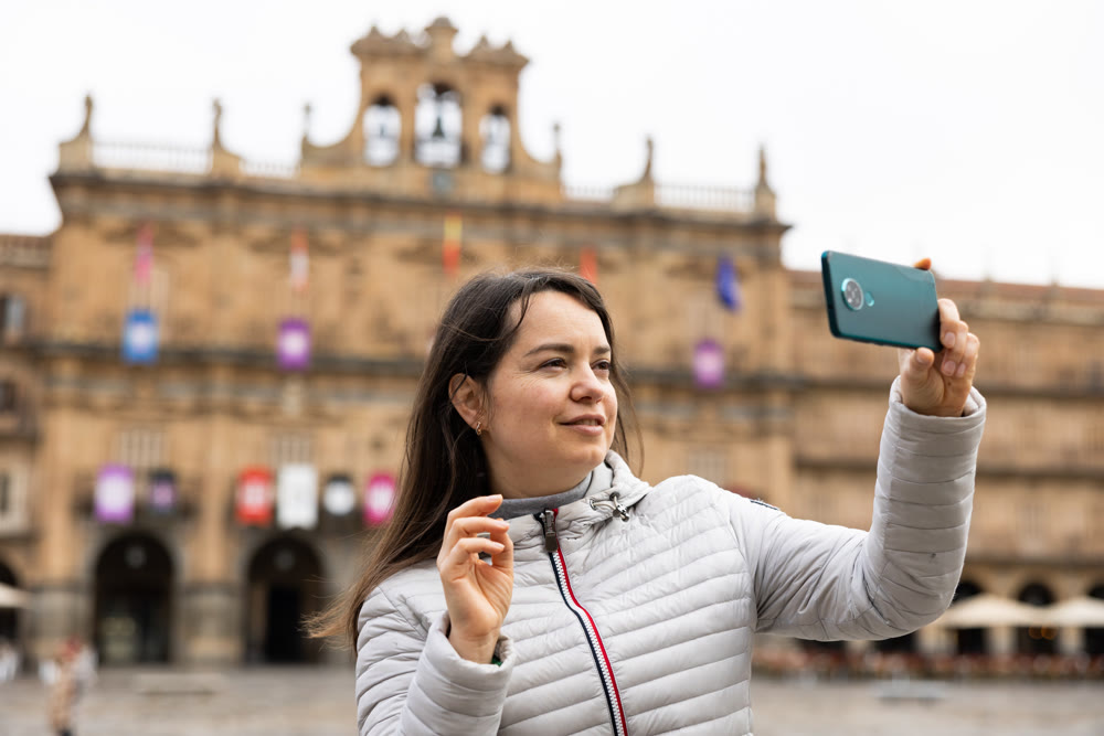 Woman is taking photos on her camera while journey through the Plaza Mayor. Spain