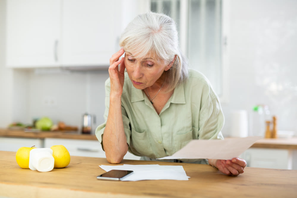 Worried mature woman checking papers at home