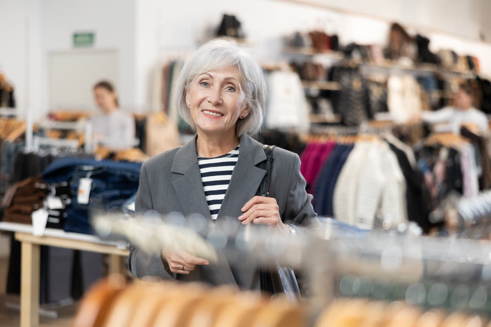 Old woman watching excitedly large stock of clothes in clothing store