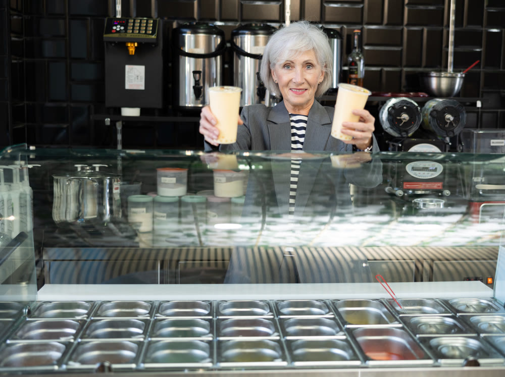 Smiling senior saleswoman offering refreshing Taiwanese boba tea