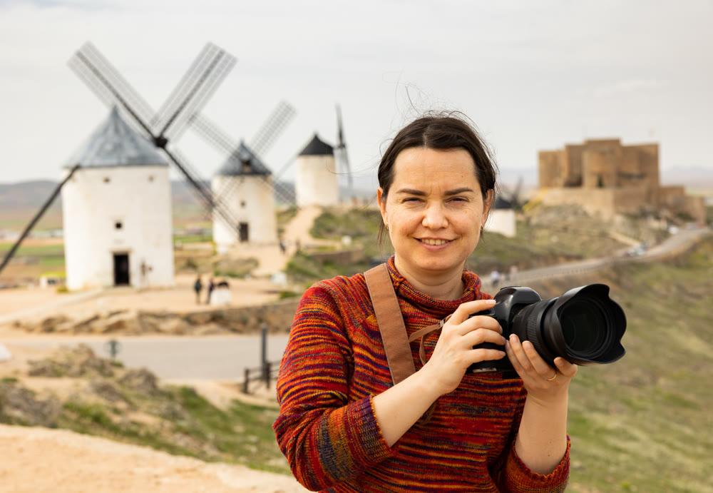 Woman tourist takes pictures of the windmills of city of Consuegra. Spain