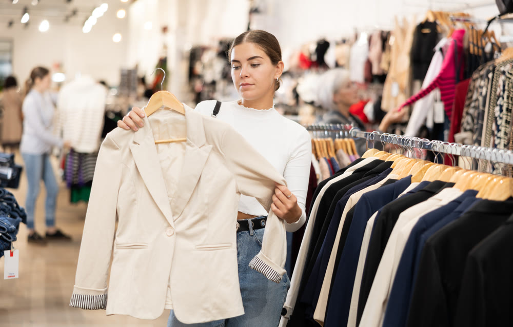 Young woman choosing blazer in store