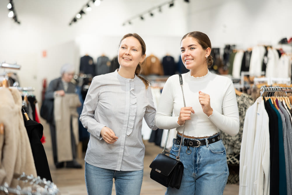 Adult and young women walk through clothing store
