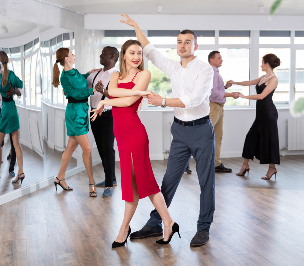 Dance studio - group of beautifully dressed people learn to dance tango