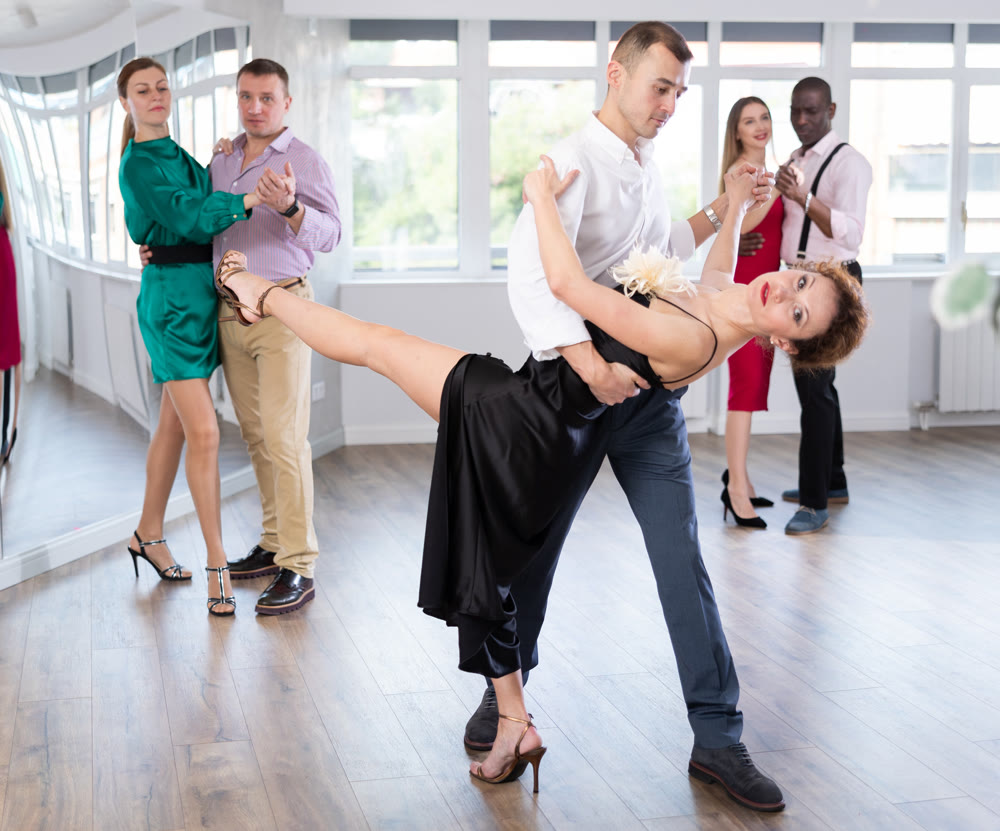 Woman and young man practicing waltz in dancing studio