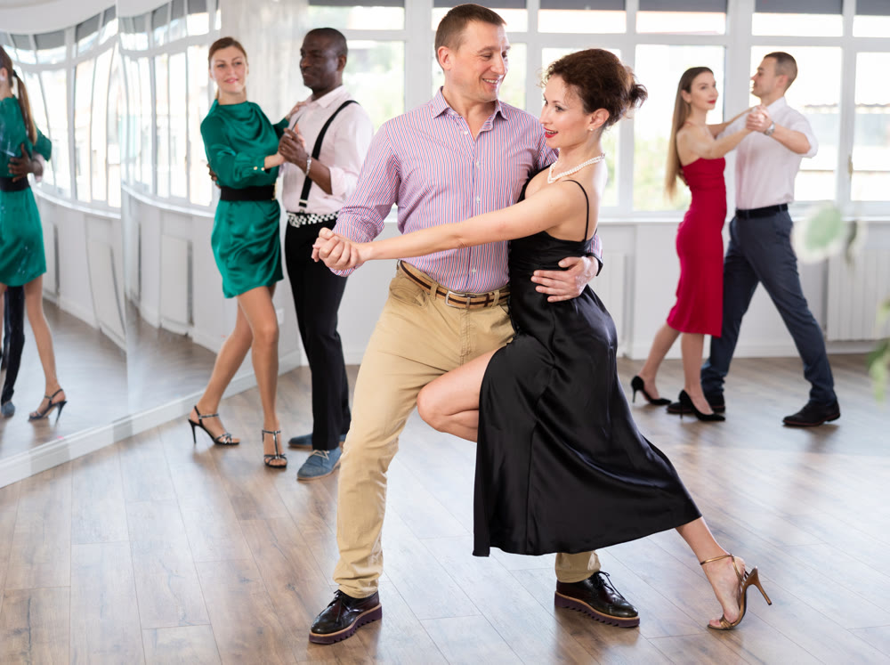 Middle-aged man and woman practicing waltz in dancing studio