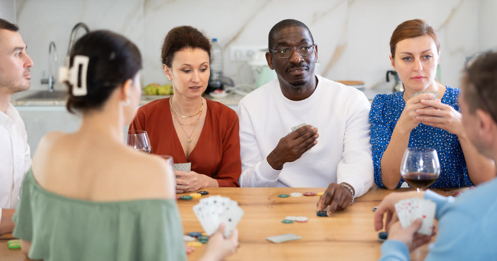Joyful middle-aged men and women playing poker at home