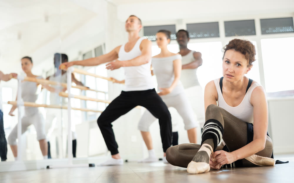 Woman dancer tying ribbons on pointe shoes