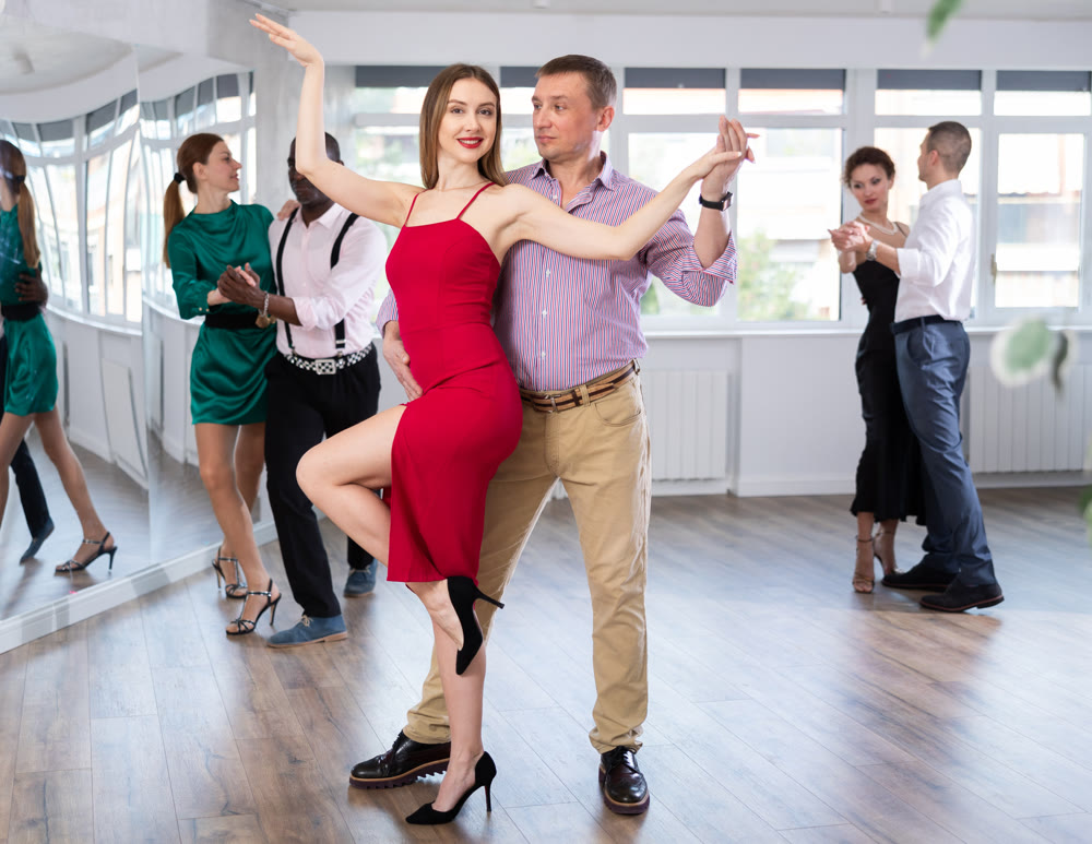Woman enjoying passionate Latin American dancing with male partner in dance hall