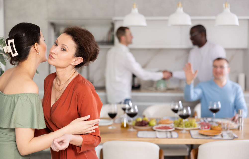Hospitable hostess warmly greeting and kissing female friend